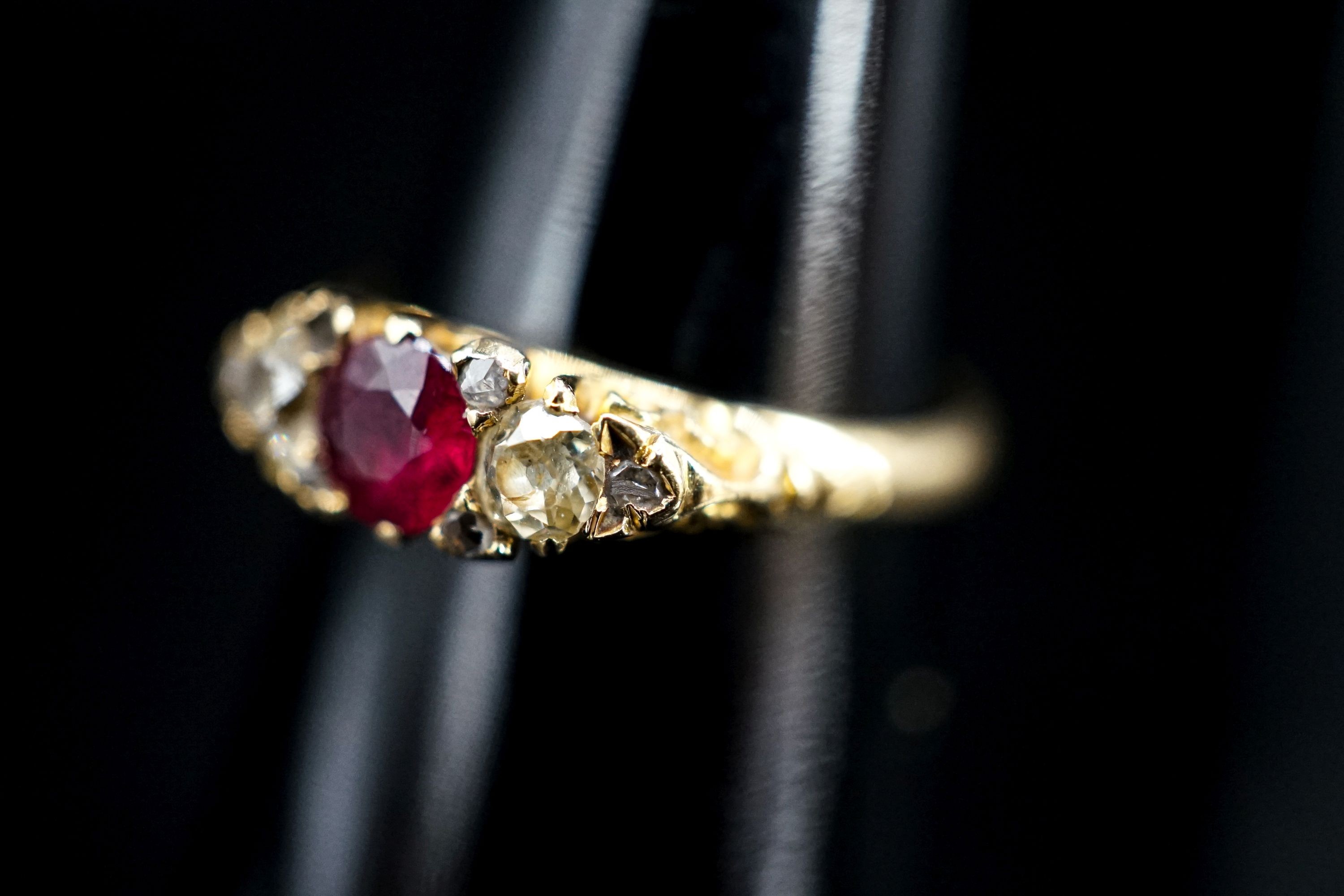 An Edwardian 18ct gold, ruby and diamond three stone ring, with diamond chip spacers (one missing), size N, gross weight 3.3 grams.